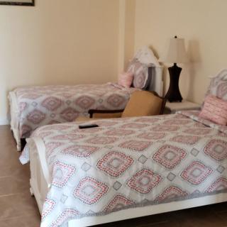 A cozy bedroom with two neatly arranged beds and decorative pillows, accompanied by a lamp and a chair.