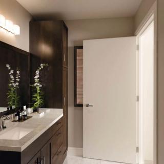 A modern bathroom with a sleek design featuring a large mirror, dark cabinets, and minimal decor.