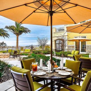 An inviting outdoor dining area with tables set under large umbrellas, offering a view of palm trees and the beachfront.