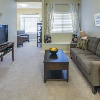 A cozy living room with modern furnishings, featuring a sofa, coffee table, and television.