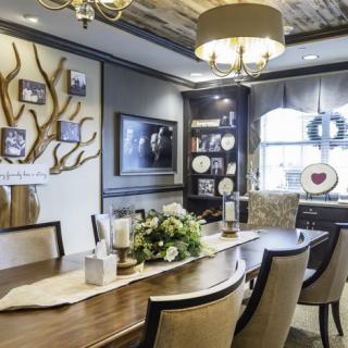 A beautifully designed dining room featuring a long wooden table, elegant chairs, and decorative elements including wall art and plates.