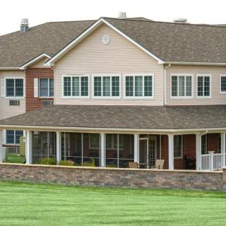 A two-story house with a large lawn and spacious porch.