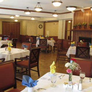 An elegant dining room with neatly arranged tables and chairs, featuring place settings and floral decorations.