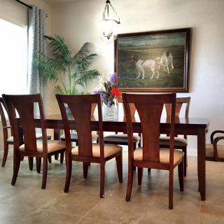 A well-decorated dining room featuring a wooden table and chairs, adorned with plants and wall art.