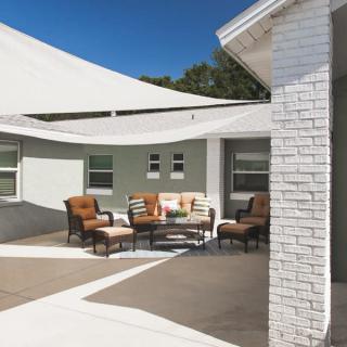A modern patio setup featuring comfortable outdoor furniture and a shade sail.