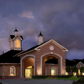 A beautifully lit building against a dramatic cloudy sky at night.