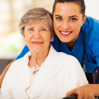 A caregiver and an elderly woman smiling together.