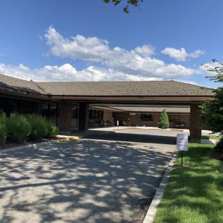 A building with a covered entrance and driveway on a sunny day.