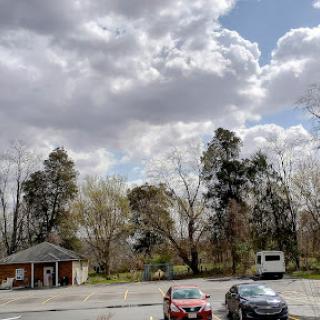 A serene view of a parking lot surrounded by trees under a cloudy sky.