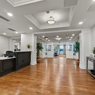 A modern and spacious office reception area with a wooden floor, reception desk, and decorative plants.