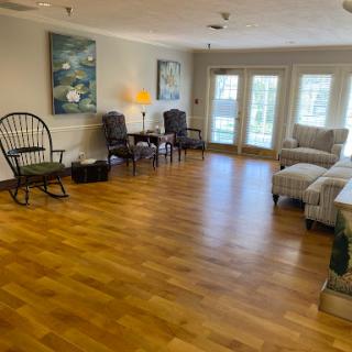 A spacious and inviting living room filled with natural light, featuring comfortable seating and a warm wooden floor.