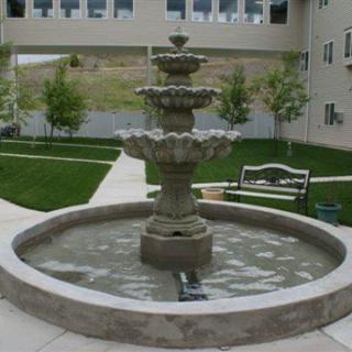 A multi-tiered stone fountain in a landscaped garden area.