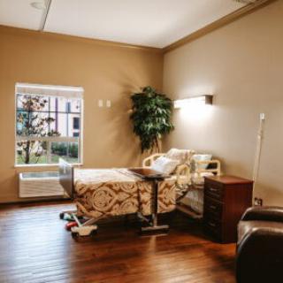 An empty hospital room with a single bed and window providing natural light.