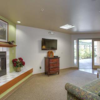 A cozy living room featuring a fireplace, wall-mounted television, and comfortable seating with ample natural light.