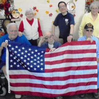 A group of people posing indoors with an American flag.