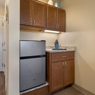 Compact kitchen space with a mini fridge and wooden cabinets.