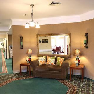 A cozy hotel lobby with a sofa, elegant mirror, and decorative lighting.