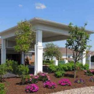 A landscaped garden with vibrant flowers and trees surrounding a white outdoor pavilion.