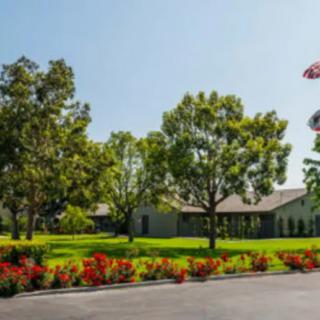 A scenic view of a building surrounded by trees and colorful flowers in a garden.
