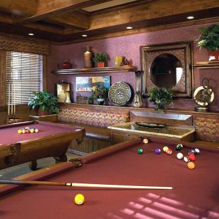 A cozy game room featuring a beautifully designed pool table with wooden accents and elegant decor.