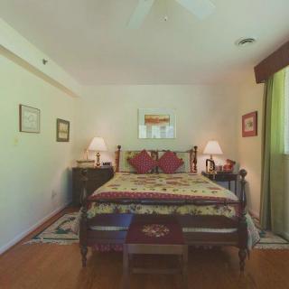 A cozy bedroom featuring a large bed with decorative pillows, bedside tables with lamps, and framed artwork on the walls.
