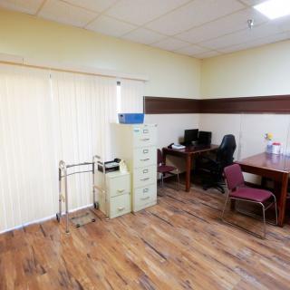 An office workspace with a desk, computer, filing cabinet, and wooden flooring.