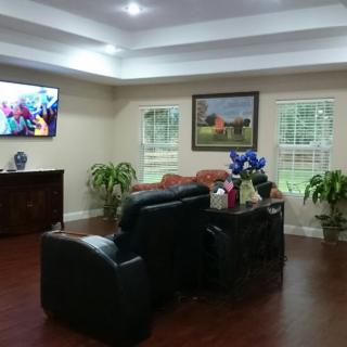 A cozy living room with comfortable seating, a television, and decorative plants.