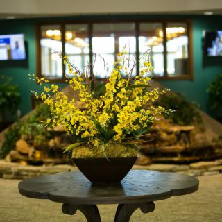 A vibrant yellow floral arrangement on a table in a lobby setting.