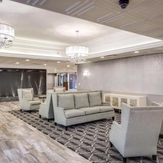 A modern lobby with neutral-colored furniture and elegant chandeliers.