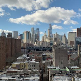 A stunning view of the New York City skyline under a bright blue sky with fluffy clouds.