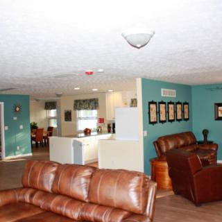 An open-concept living room with leather sofas and a view of the kitchen.