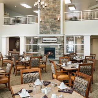 A modern dining area with stylish furniture, a stone fireplace, and a view of the upper level.