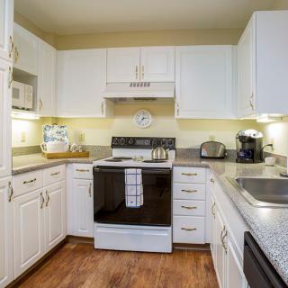 A modern kitchen with white cabinets, featuring a stove and various appliances.