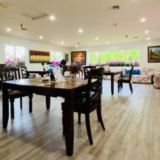 A spacious and well-lit restaurant dining area with wooden floors, decorated with artwork on the walls.