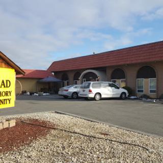 A view of a building with a prominent sign and parked vehicles in the foreground.