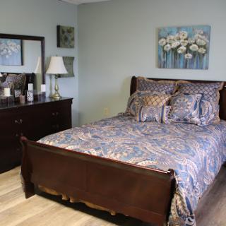 A cozy and well-decorated bedroom featuring a stylish bed, elegant lamp, and beautiful artwork.