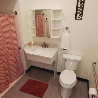 A tidy bathroom with a red shower curtain, white sink, toilet, and mirror.