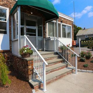 Entrance to a brick building with an awning and stairs adorned with flowers.