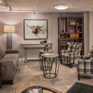 A cozy living room with stylish furniture and decor, featuring a sofa, two armchairs, a lamp, and artwork on the wall.