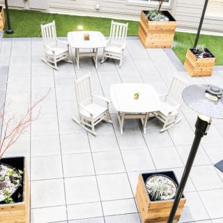 A neatly arranged outdoor patio featuring tables, chairs, and planters.