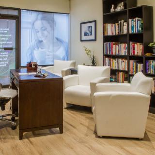 A cozy and professional office space with comfortable seating and a well-stocked bookshelf.