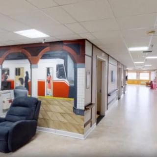 A hallway featuring a mural of a train scene with a comfortable recliner placed nearby.