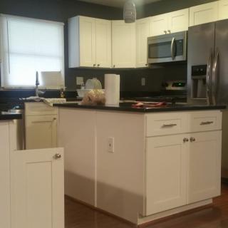 A modern kitchen with white cabinets, a central island, and stainless steel appliances.