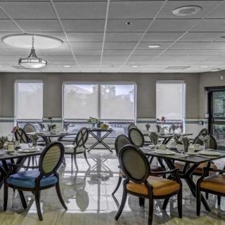 A modern restaurant dining area with elegantly arranged tables and chairs, featuring large windows and stylish decor.