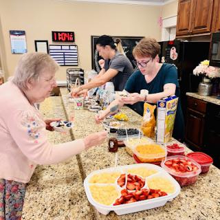 Volunteers preparing snacks in a welcoming kitchen environment for residents.