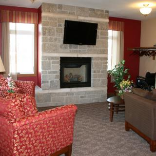 A cozy living room with a stone fireplace, TV mounted above, and comfortable seating.