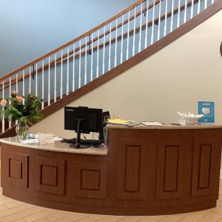 A reception desk in front of a staircase in an office setting.