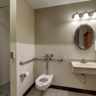 A modern accessible bathroom featuring a toilet, sink, and grab bars.