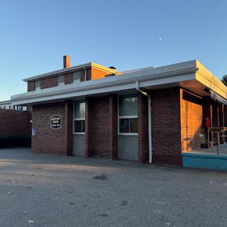 A brick building with a flat roof and blue trim, illuminated by the warm glow of sunset.