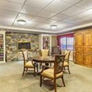 A cozy dining room with a stone fireplace, surrounded by bookshelves and wooden cabinets.